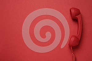 Corded telephone handset on red background  top view. Hotline concept