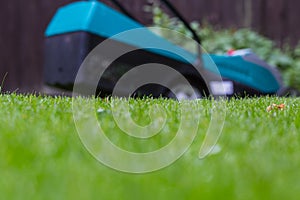 Cordless battery power lawn mower close up on green grass background