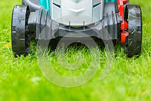 Cordless battery power lawn mower close up on green grass background