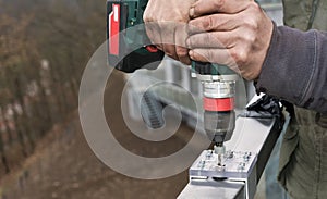 Cordless drilling machine in workman hands. Jig bushing of aluminum and acrylic glass