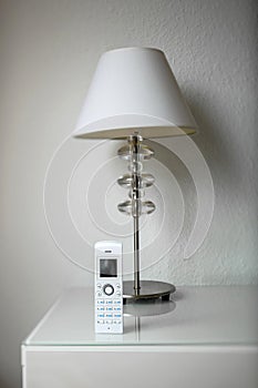 Cordless phone next to a desk lamp