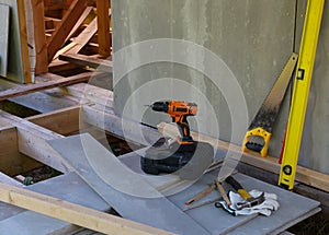 cordless screwdriver as well as a frayed hammer, ruler and protective gloves on the construction site. construction and