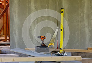 cordless screwdriver as well as a frayed hammer, ruler and protective gloves on the construction site. construction and renovation