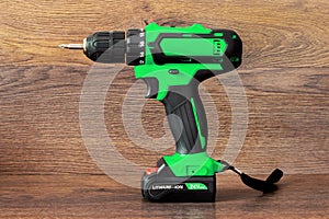 Cordless screwdriver with bits for tightening screws on a wooden background