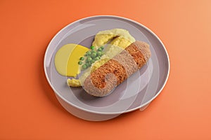 Cordon bleu cutlet, deep fried meat served with mashed potatoes and green peas on gray plate over orange background