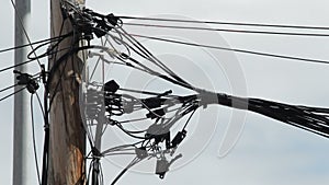 Cords wire of different services badly installed on a wooden pole