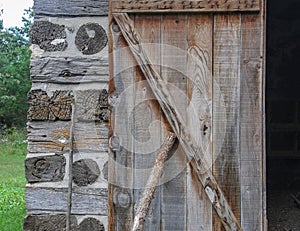 Cordwood and log beams with an old wooden door at Old World Wisconsin