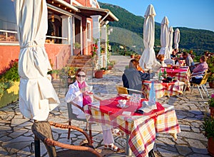 CORFU ISLAND, GREECE, JUNE 03, 2014: Young pretty woman is having dinner in classical Greek taverna restaurant cafe. Tourists and