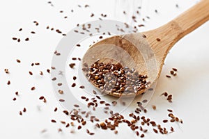 Coriander and flax seeds pouring into wooden spoon