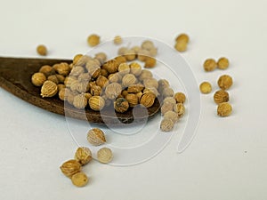 coriander grains on a wooden spoon on a white background