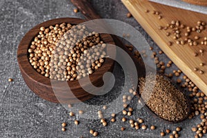 Coriander powder and coriander beans in a wooden spoon. Dry coriander. Coriander seed spice.