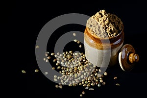 Coriander Powder and seeds on black background.