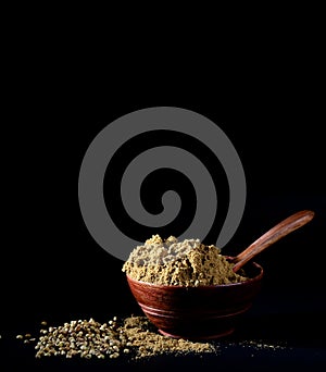 Coriander Powder and seeds on black background.