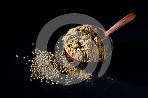 Coriander Powder and seeds on black background.