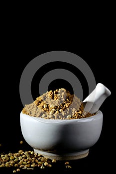 Coriander Powder and seeds with mortar and pestle on black background