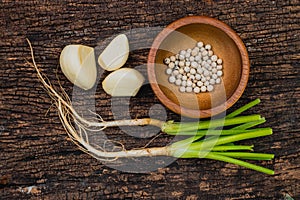 Coriander root Garlic and Pepper seeds or Three kings of Thai food ingredient shot on wooden old rustic background