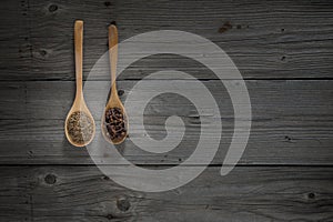 Coriander seed and spice clove on wooden spoons and wooden background