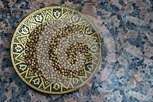 Coriander seeds on metal tray with oriental (middle eastern) motifs