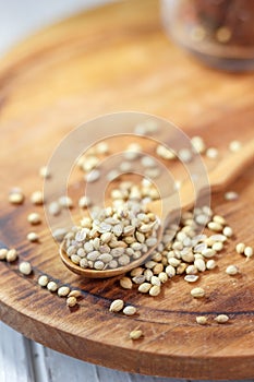 Coriander seeds in a wooden spoon over kitchen board.