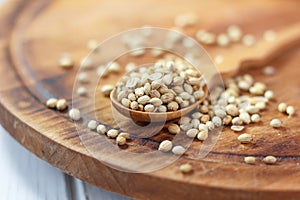 Coriander seeds in a wooden spoon over kitchen board.