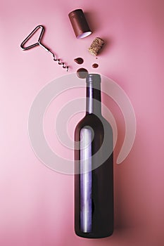 cork from a wine bottle corkscrew shrink wrap and drops of red wine on a pink background