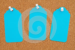 Corkboard with 3 blue gift tags and pushpin