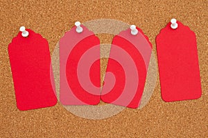 Corkboard with 4 red gift tags and pushpin