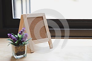 corkboard, artificial flower in small glass pot on a wooden table.