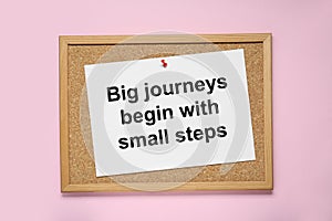 Corkboard with pinned message Big Journeys Begin With Small Steps on pink background, top view. Motivational quote