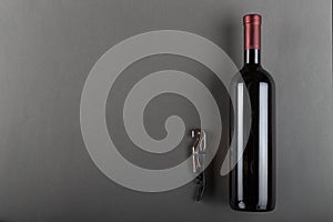 Corked bottle of red wine and corkscrew on a gray background. Alcoholic drink. Winemaking concept. Space for text