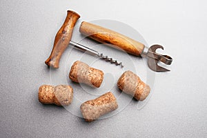 Corkscrew, bottle opener and wine corks on a gray background