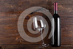 Corkscrew, glass and bottle of red wine on a wooden background. Top view