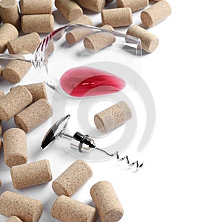 Corkscrew, glass with red wine and stoppers on white background