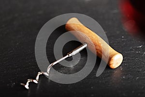 Corkscrew opener for wine cork on dark wooden background. Bottl