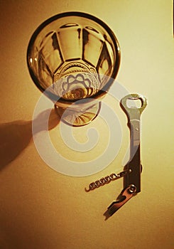 Corkscrew for opening bottles and a glass on a gray background.