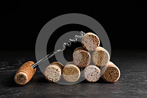 Corkscrew and stack of wine bottle stoppers on slate table, closeup