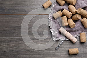 Corkscrew and wine bottle stoppers with napkin on wooden table, flat lay. Space for text