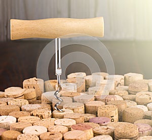 Corkscrew with a wooden handle against the background of wine bottle corks