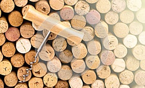 Corkscrew with a wooden handle against the background of wine bottle corks