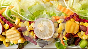 Corn, beetroot, carrot, red bean, and lettuce on a white plate