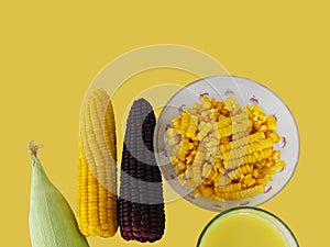 Corn, boiled yellow and purple corn, corn sliced in a cup, milk in glass and fresh corn on the cob