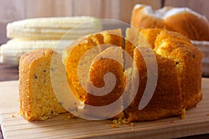 Corn cake sliced on wooden board on rustic wooden table for breakfast. Typical Brazilian food. Front view