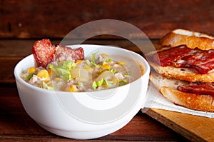 Corn chowder soup with bacon. Brown wooden background. Close-up view