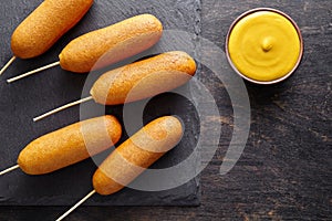 Corn dog traditional American corndog street junk food deep fried hot meat sausage snack with yellow mustard