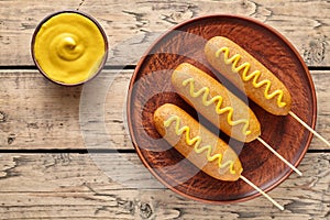 Corn dog traditional American corndog street junk food deep fried hotdog meat sausage snack with yellow mustard photo