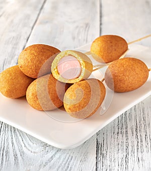 Corn dogs on white serving plate