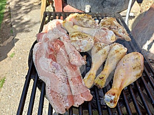 Corn fed chicken thighs and drumsticks with outdoor pork belly prepared on a charcoal grill