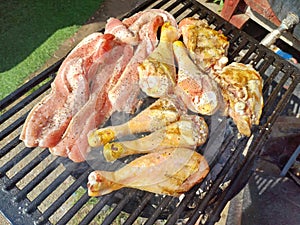 Corn fed chicken thighs and drumsticks with outdoor pork belly prepared on a charcoal grill