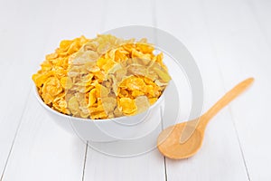 Corn flakes bowl with spoon on white wooden