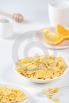 Corn flakes bowl sweeties with milk and orange on white background, close up, fresh and healthy breakfast design concept